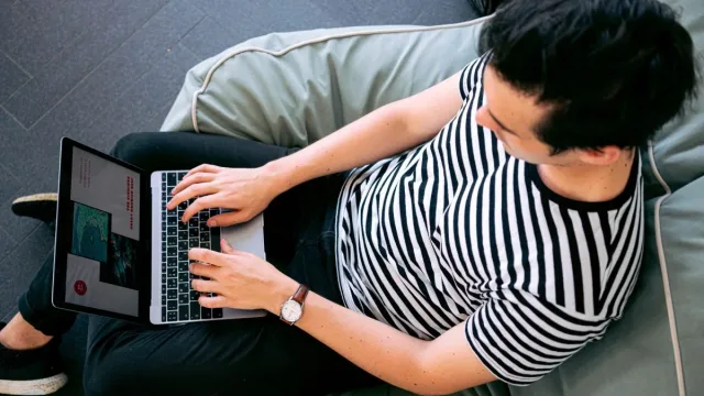 guy sitting on a couch on his laptop using canva.com